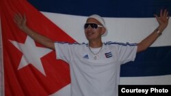 Juan Carlos Hernández Mora junto a la bandera cubana.