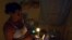 Una mujer prepara unos platos de comida en la cocina, iluminada con velas, en un apagón en el barrio de Alamar